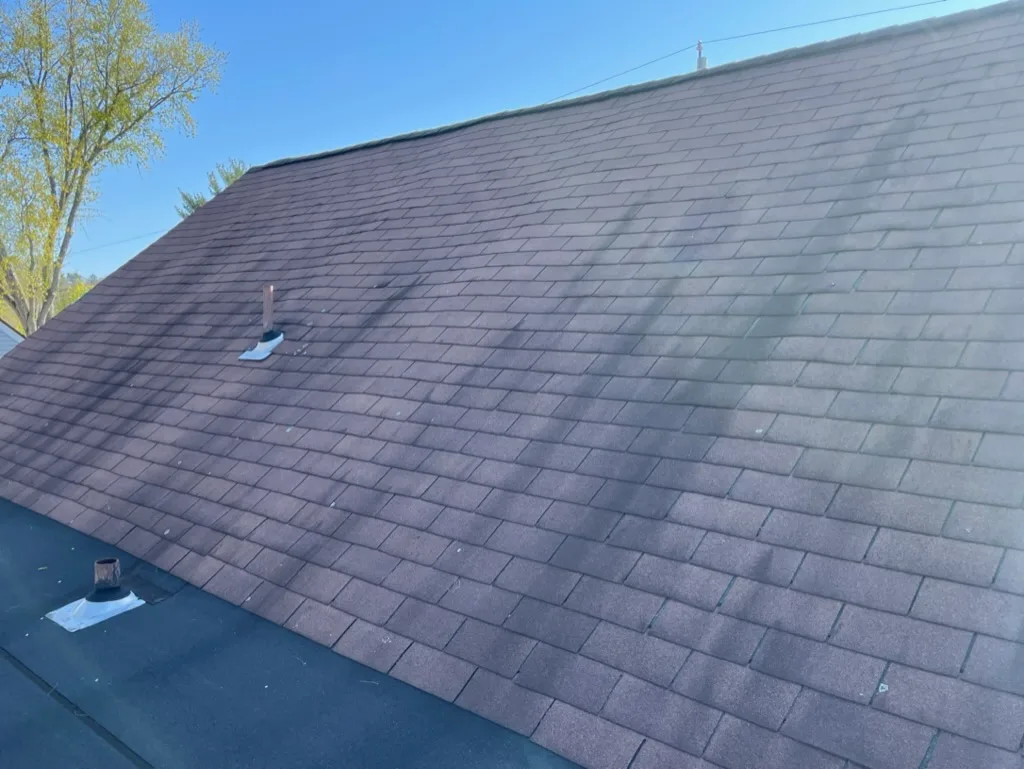 Black algae streaks running down a brown asphalt shingle roof before a soft wash, Dutchess County NY