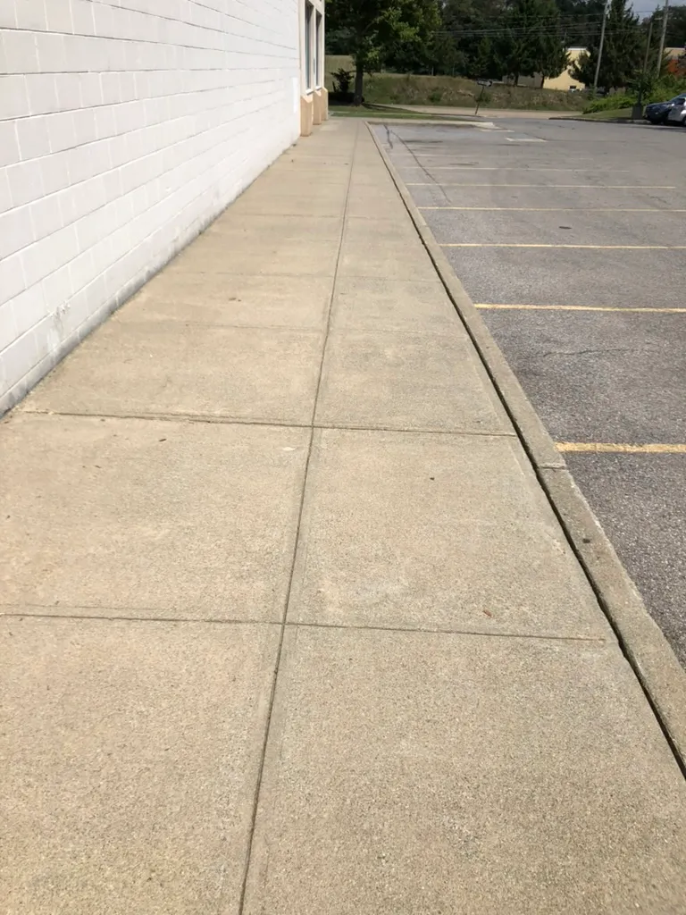 Clean concrete sidewalk along a commercial building after professional pressure washing in Dutchess County, NY