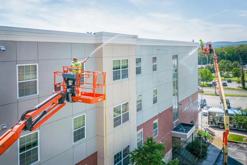 MJK Solutions crew washing a multi-story commercial building from two boom lifts, Hudson Valley NY