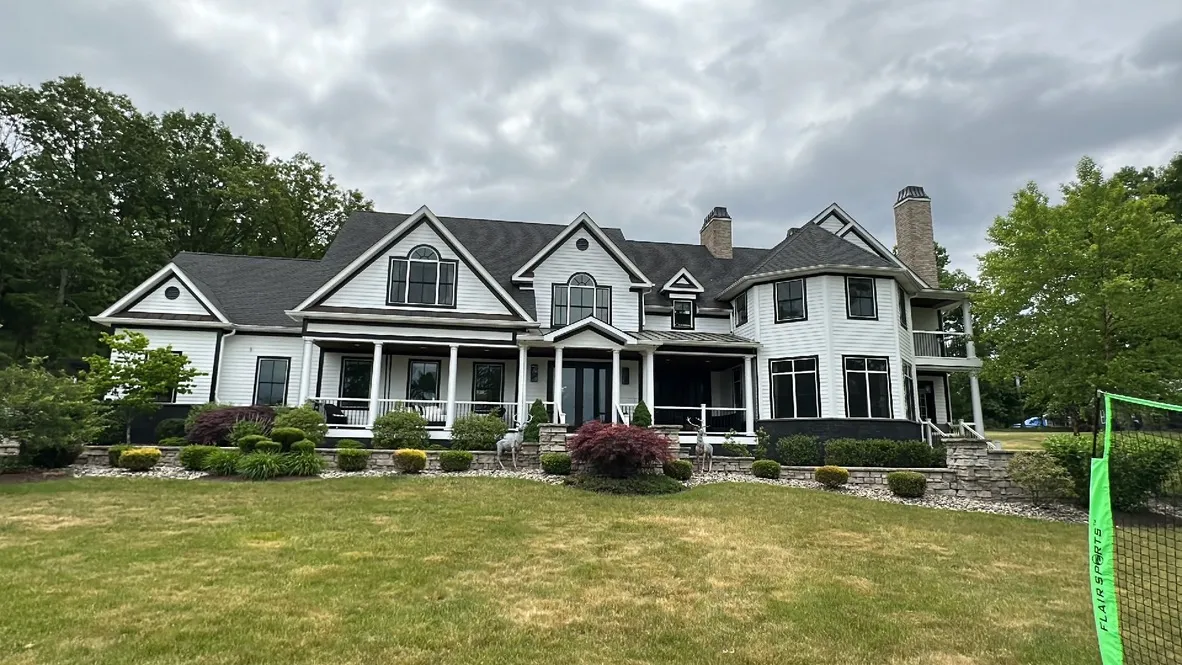 Large white colonial home with dark roof after professional house washing in Dutchess County, NY