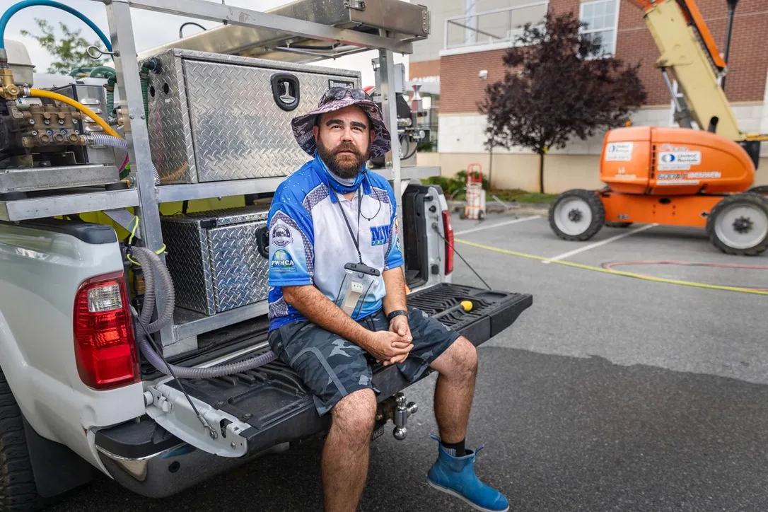Matt Krutick, owner of MJK Solutions, sitting on the tailgate of the company soft wash truck at a commercial cleaning job in Dutchess County, NY