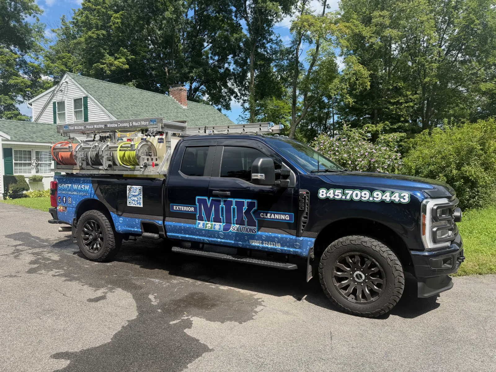 MJK Solutions black soft wash truck with the rig loaded, parked in a driveway in Poughkeepsie, NY