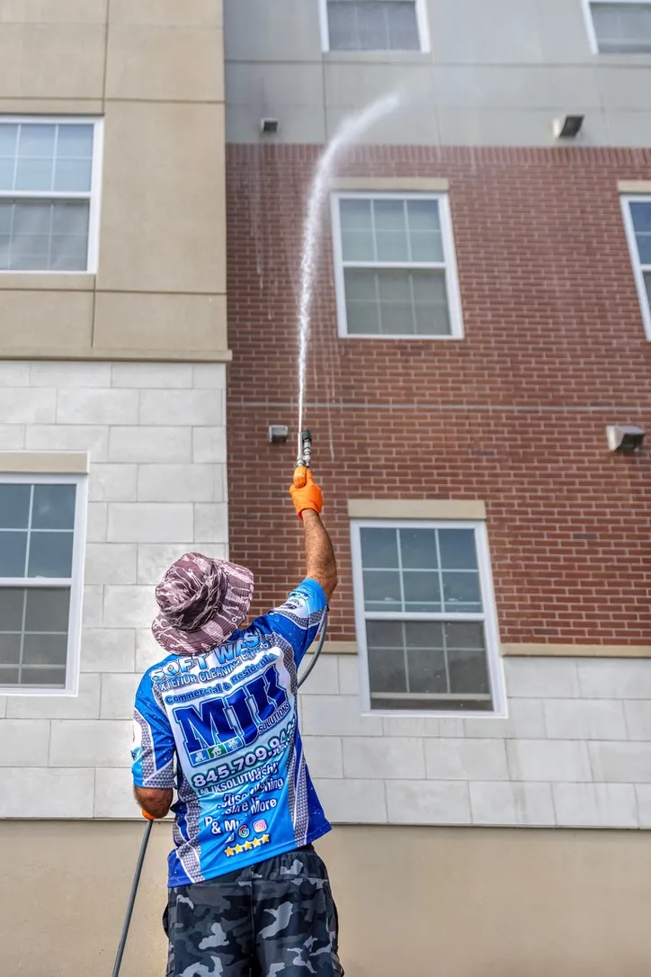 MJK Solutions technician soft washing the brick and stucco exterior of a commercial building in Dutchess County, NY