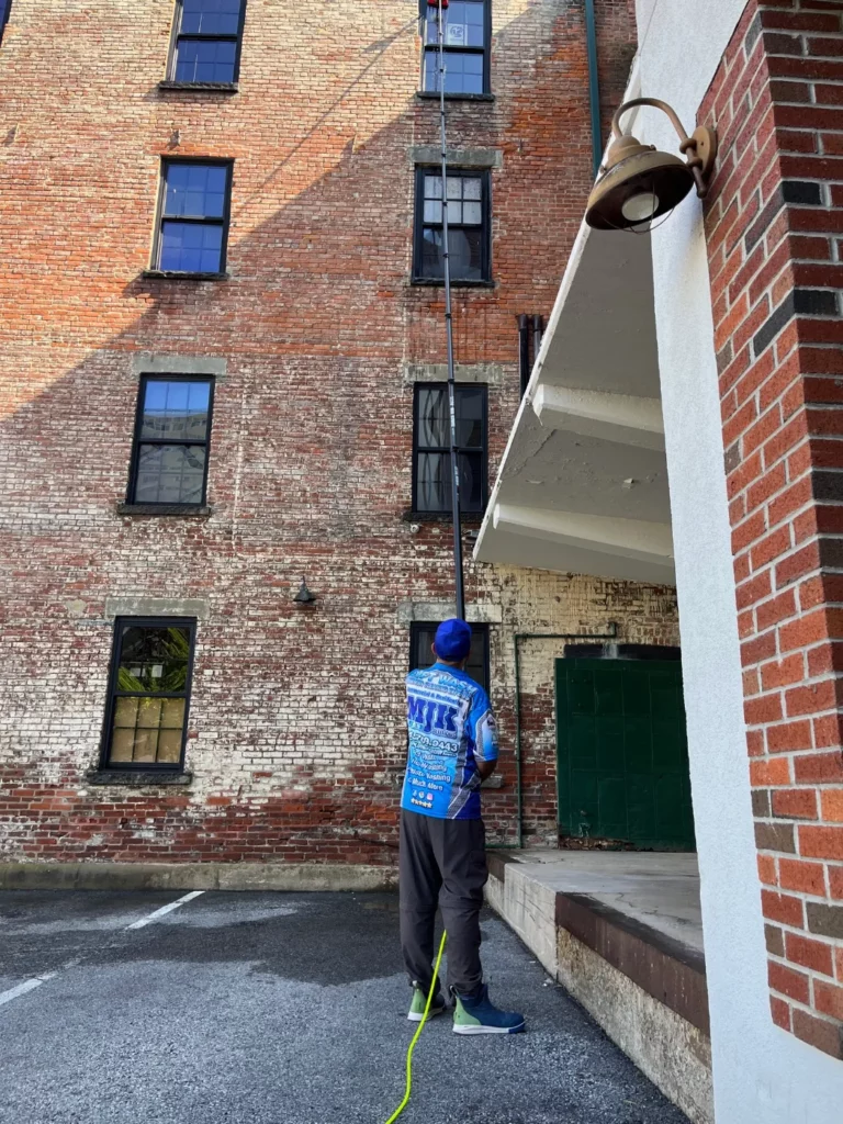 MJK Solutions technician soft washing the brick exterior of a multi-story commercial building in the Hudson Valley